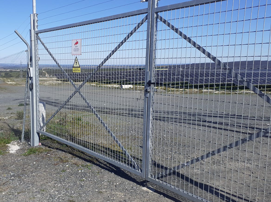 Grote dubbele metalen poort bij het zonnepark met elektronische vergrendelingstechniek.