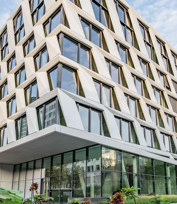 Moderne kantoorgebouwenarchitectuur van het ONE PLAZA-project met een opvallende gevel en grote glaspartijen.
